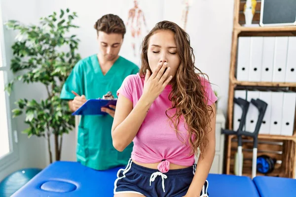 Young Hispanic Woman Physiotherapist Appointment Bored Yawning Tired Covering Mouth — Stockfoto