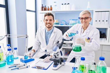 Mother and son scientist partners measuring liquid at laboratory