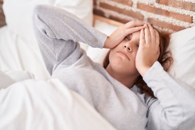 Young beautiful plus size woman stressed lying on bed at bedroom