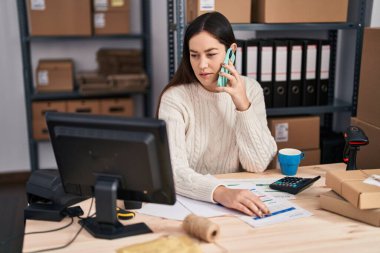 Genç kadın dış ticaret işçisi ofisteki akıllı telefondan konuşuyor.