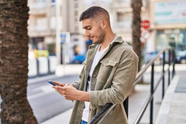 Sokakta akıllı telefon kullanan, kendine güvenen genç bir İspanyol.