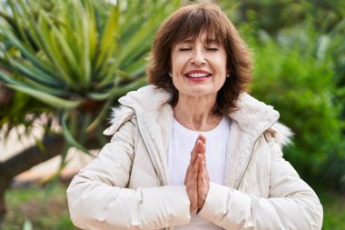 Orta yaşlı kadın parkta yoga egzersizi yapıyor.