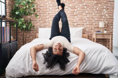 Yatakta uzanmış, yatak odasında kendine güvenen genç latin adam.