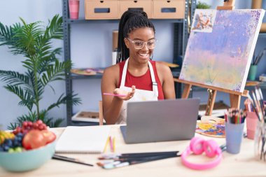 Afrikalı Amerikalı kadın sanatçı resim stüdyosunda online çizim dersi alıyor.