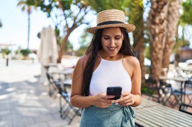 Sokakta akıllı telefon kullanan, kendine güvenen genç İspanyol kadın.