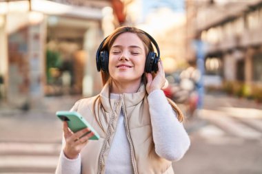 Sokakta müzik dinleyen kendine güvenen genç sarışın kadın.