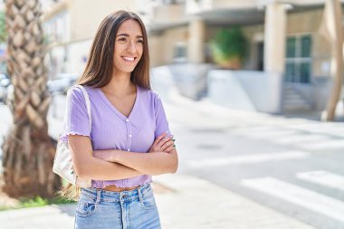 Sokakta kollarını kavuşturmuş genç, güzel İspanyol bir kadın.