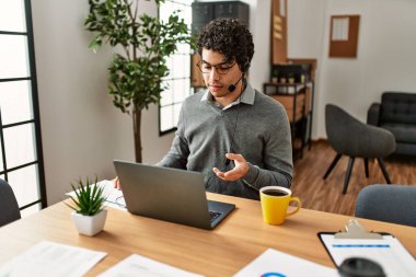 Genç Hispanik çağrı merkezi temsilcisi ofiste video görüşmesi yapıyor..