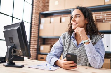 Genç İspanyol kadın ecommerce iş işçisi Ofiste akıllı telefon kullanıyor