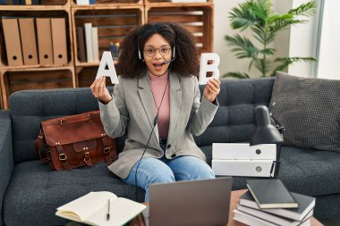 Young african american woman working speech problems at consultation office celebrating crazy and amazed for success with open eyes screaming excited. 