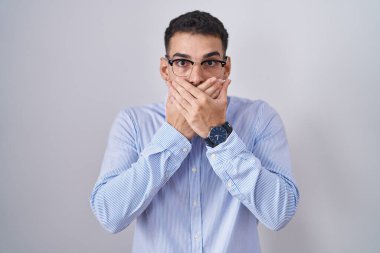 İş kıyafetleri ve gözlük takan yakışıklı İspanyol yanlışlıkla ağzı ellerle kapatmış. gizli kavram. 