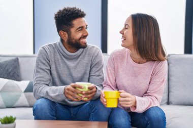 Man and woman couple sitting on sofa drinking coffee at home