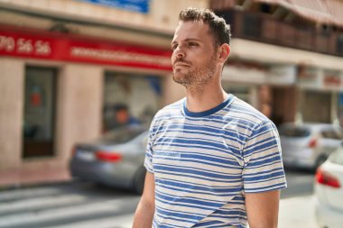 Latin kökenli genç adam ciddi bir ifadeyle sokağa bakıyor.