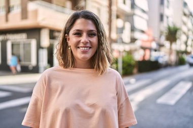 Sokakta kendinden emin gülümseyen genç İspanyol kadın.