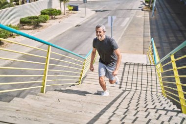 Orta yaşlı İspanyol adam spor giyer sokakta koşar.