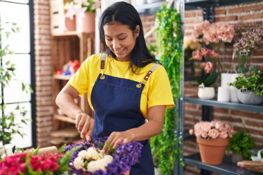Çiçekçide çiçek kesen Latin bir kadın.
