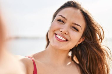 Genç ve güzel İspanyol kadın turist gülümsüyor. Kendine güveni tam. Sahilde kamerayla selfie çekiyor.