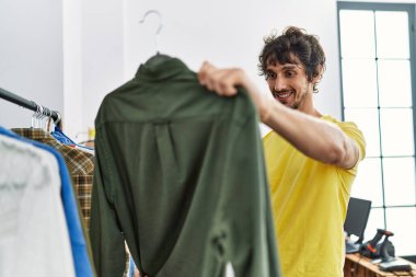 Young hispanic man smiling confident shopping at clothing store
