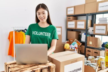 Bağış standında dizüstü bilgisayarla gülümseyen Asyalı genç bir kadın.