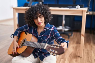 Young middle east woman musician playing classical guitar at music studio