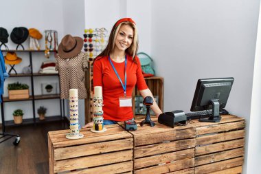 Giyim mağazasında çalışırken gülümseyen beyaz bir kadın..