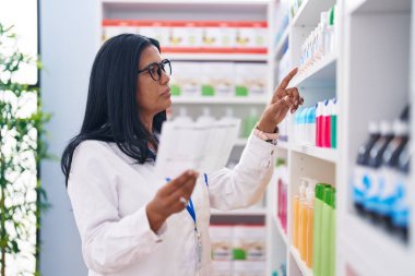 Eczanede reçete okuyan orta yaşlı İspanyol kadın eczacı.