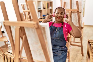 Sanat stüdyosunda müzik dinleyen kıdemli Afro-Amerikan kadın.