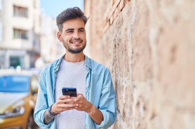 Sokakta akıllı telefon kullanan, kendine güvenen genç bir İspanyol.