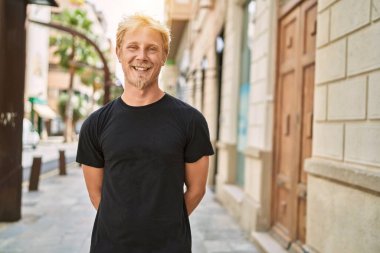 Sokakta kendinden emin gülümseyen beyaz bir genç.