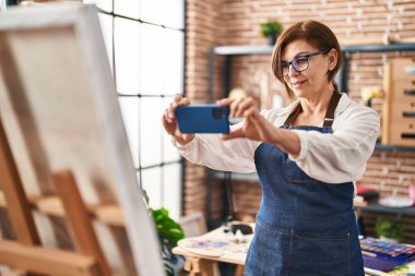 Resim stüdyosunda resim çizmek için orta yaşlı kadın sanatçı.