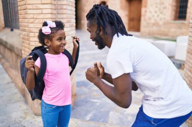 Father and daughter standing together speaking at school