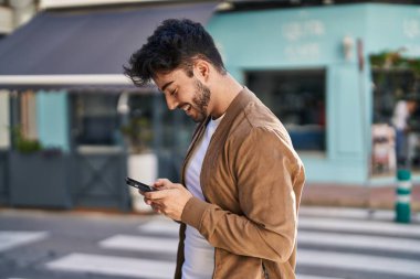 Sokakta akıllı telefon kullanan, kendine güvenen genç bir İspanyol.