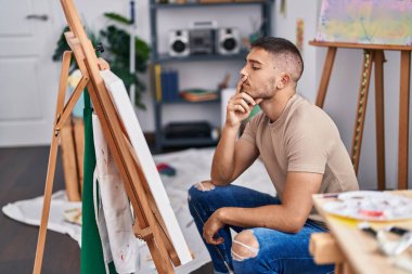 Resim stüdyosunda şüpheli bir ifadeyle çizim yapan genç bir İspanyol.