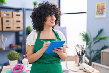 Young middle east woman artist smiling confident drawing on touchpad at art studio