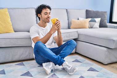 Genç İspanyol adam evde oturmuş kahve içiyor.