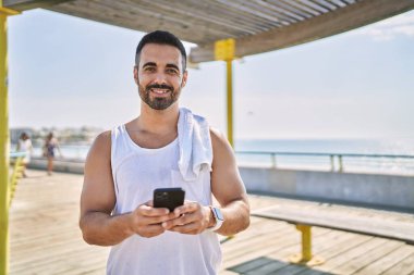 Güneşli bir günde spor yapan İspanyol sporcu akıllı telefonu açık havada kullanır.