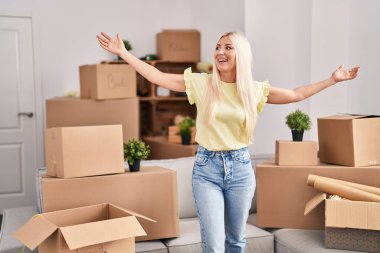 Yeni evinde kollarını açmış genç sarışın kadın.