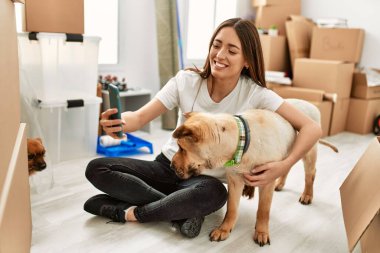 Genç İspanyol kadın kendine güveni tam. Yeni evinde yerde oturan akıllı telefonun yanında selfie çekiyor.