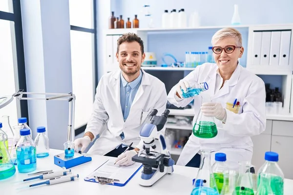 Mother and son scientist partners measuring liquid at laboratory