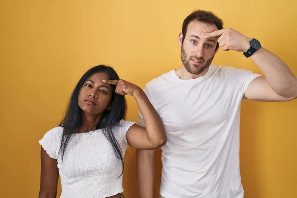 Interracial Couple Standing Yellow Background Pointing Unhappy Pimple Forehead Ugly — Stock Photo, Image