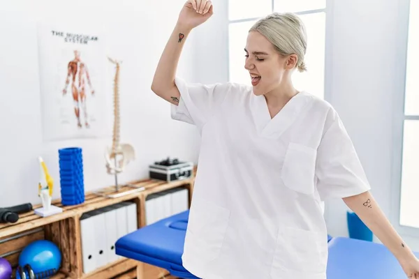 Young caucasian woman working at pain recovery clinic dancing happy and cheerful, smiling moving casual and confident listening to music