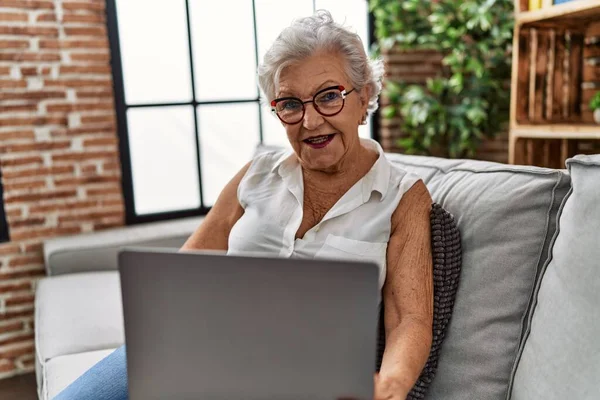 Ηλικιωμένη Γκριζομάλλα Γυναίκα Που Χρησιμοποιεί Φορητό Υπολογιστή Κάθεται Στον Καναπέ — Φωτογραφία Αρχείου