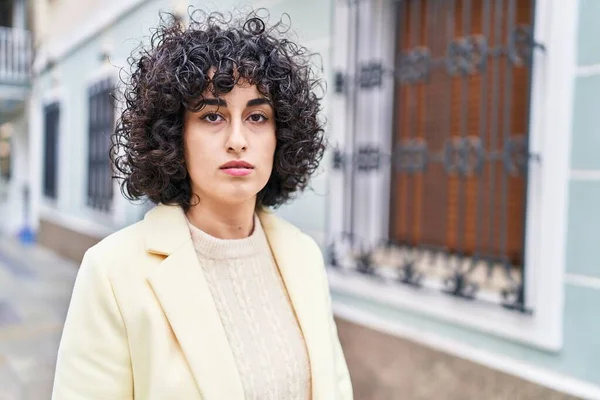 Young middle east woman executive standing with serious expression at street