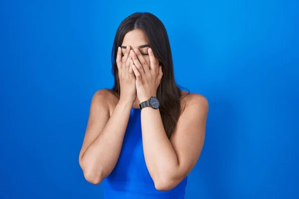 Mulher Hispânica Sobre Fundo Azul Com Expressão Triste Cobrindo Rosto — Fotografia de Stock