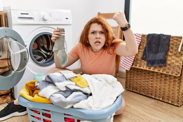 若い赤毛の女性は怒って洗濯機に汚れた洗濯機を入れて怒って怒って叫びながら拳をフラストレーションと激怒させました 怒りと攻撃的な考え方 — ストック写真