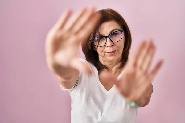 中年惊慌失措的女人站在粉红的背景上 用手和手指 镜头透视 — 图库照片