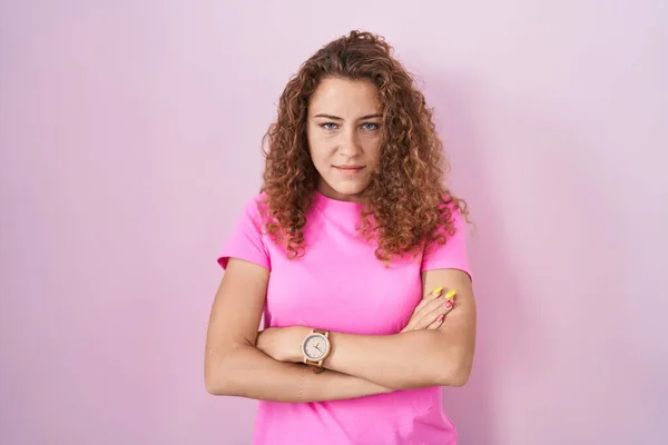Young caucasian woman standing over pink background skeptic and nervous, disapproving expression on face with crossed arms. negative person.