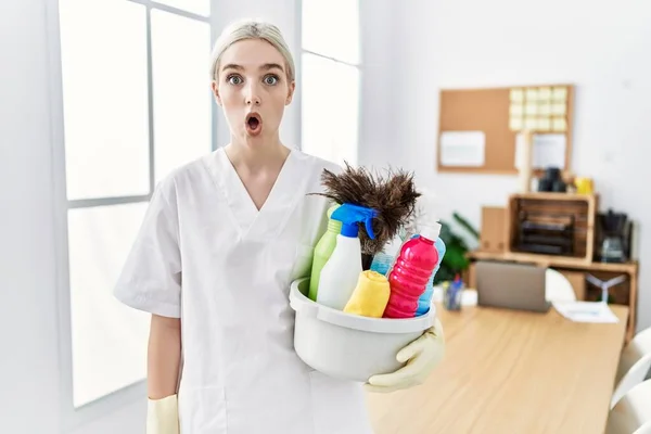 清潔な制服を着た若い白人女性が掃除機オフィスを怖がらせ 驚きのために口を開けて驚いて 不信顔 — ストック写真