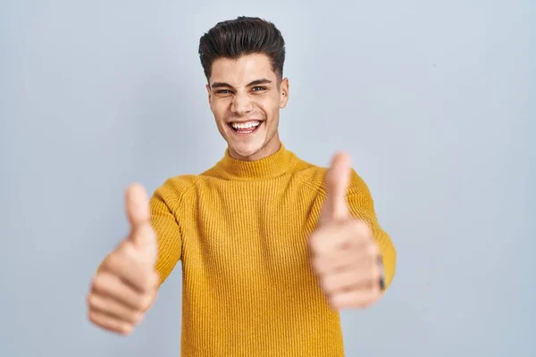 Homem Hispânico Jovem Sobre Fundo Azul Aprovando Fazer Gesto Positivo — Fotografia de Stock