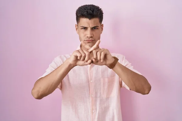 Mladý Hispánec Muž Stojící Nad Růžové Pozadí Odmítnutí Výraz Kříž — Stock fotografie